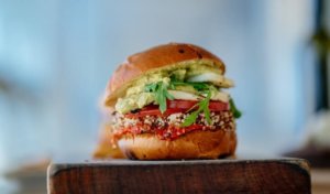 A plant-based burger sits on a wooden block
