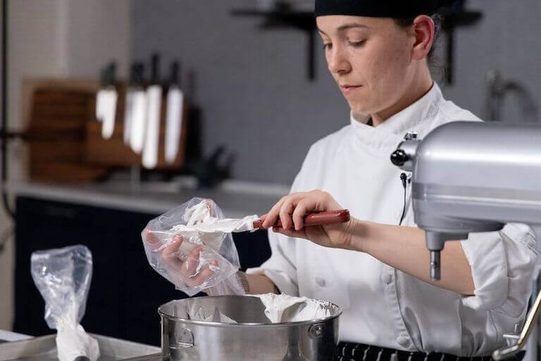Pastry chef putting baked Alaska into a piping bag
