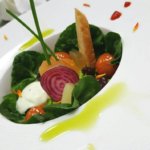 Styled greens, salad, tomatoes on a white plate