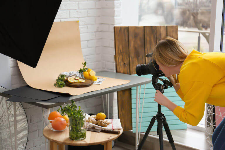 Young woman food photographer taking picture of lemons mint and ginger in professional studio