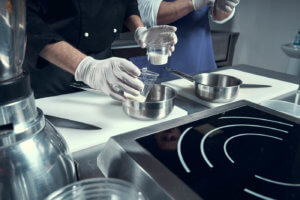 A chef is preparing a dish in a pan on the stove