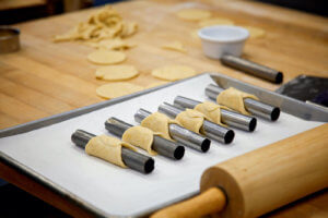 Carefully rolled dough sits on a baking sheet in a kitchen