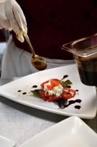 Chef adding olive oil to a Caprese salad