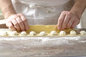 Close up of a chef rolling dough over cheese