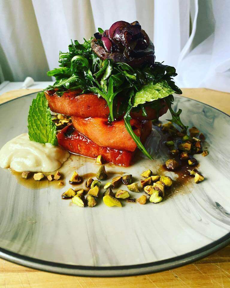 Grilled watermelon salad on a white and grey plate