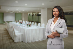 Hotel manager stands in a banquet hall holding a tablet