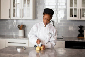 Online Escoffier student cuts dough in her kitchen