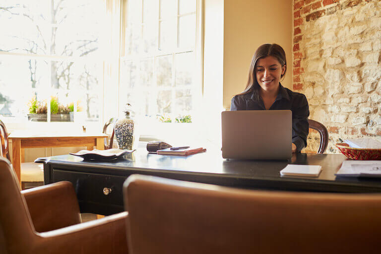 Young woman working on a laptop at the check-in desk of a hotel