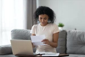 A girl smiles as she reads a letter while sitting on the couch