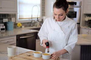 A woman uses a blowtorch on Creme Brule in the kitchen