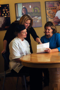 Two financial aid advisors review a paper with an Escoffier student