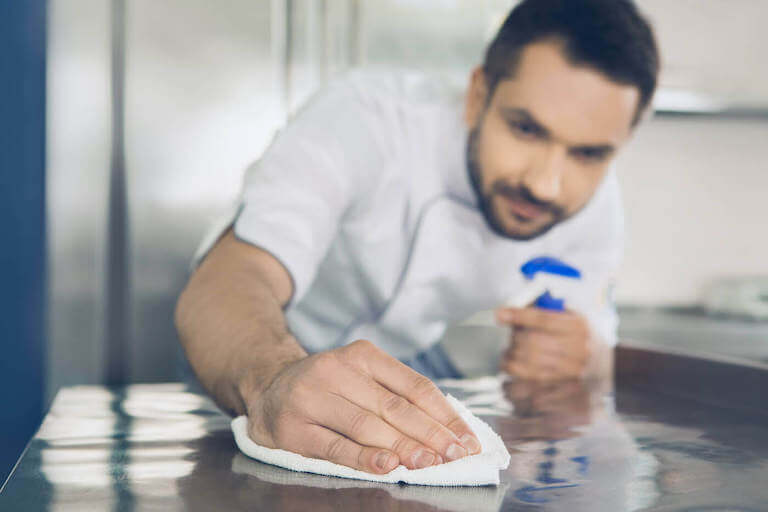 A chef is wiping the kitchen counter clean