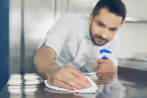 A male is chef wiping the kitchen counter clean