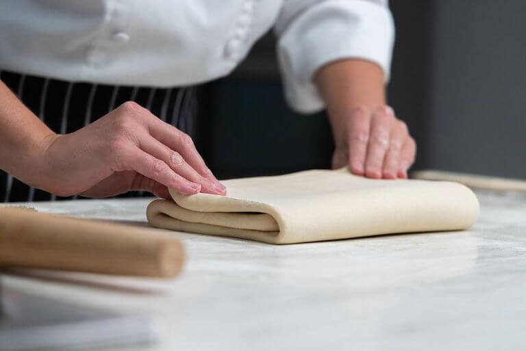 Chef folding croissant dough with their hands