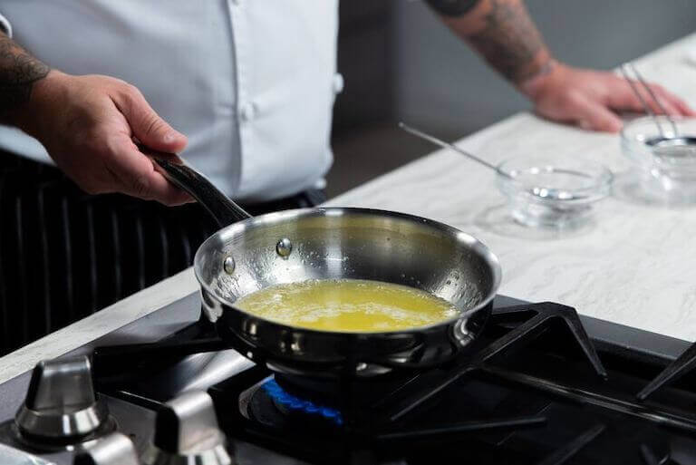 Chef melting butter in a silver pan