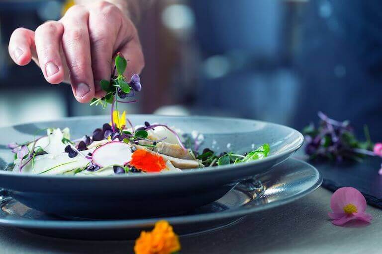 Chefs hand adding an herb garnish to a dish