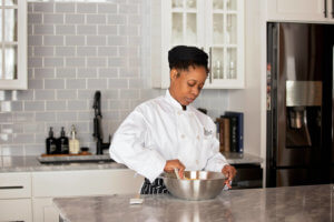 Escoffier online student kneading dough in a metal bowl