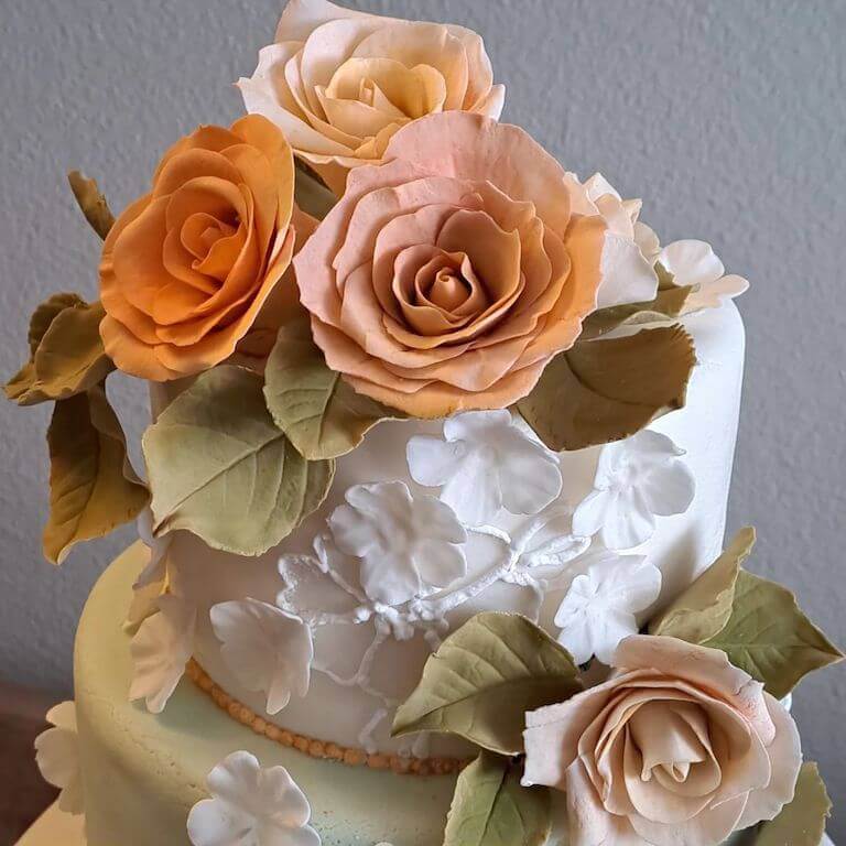Two tier cake with orange and pink flowers and light green leaves