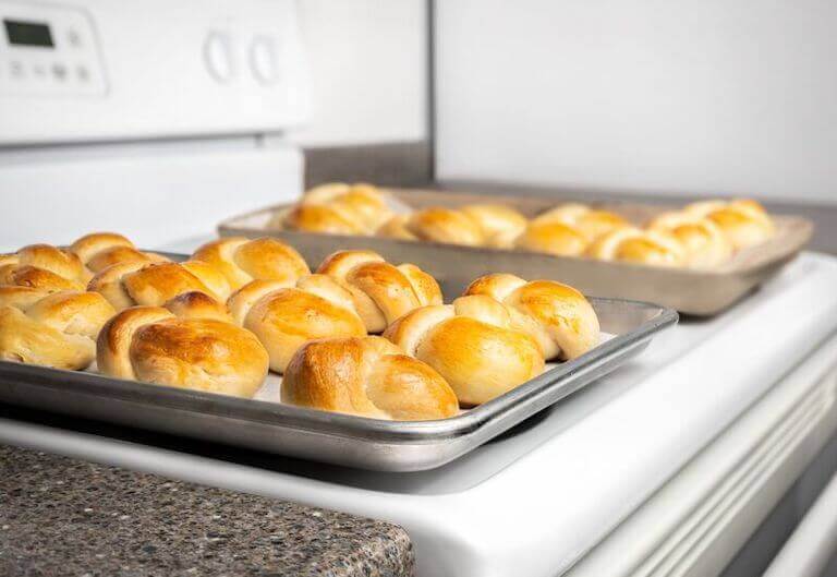  Fresh milk bread rolls on a tray sitting on the stove 
