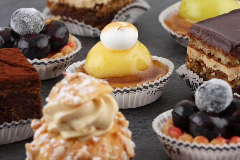 Various pastries and French Petits sit next to each other on a black tabletop