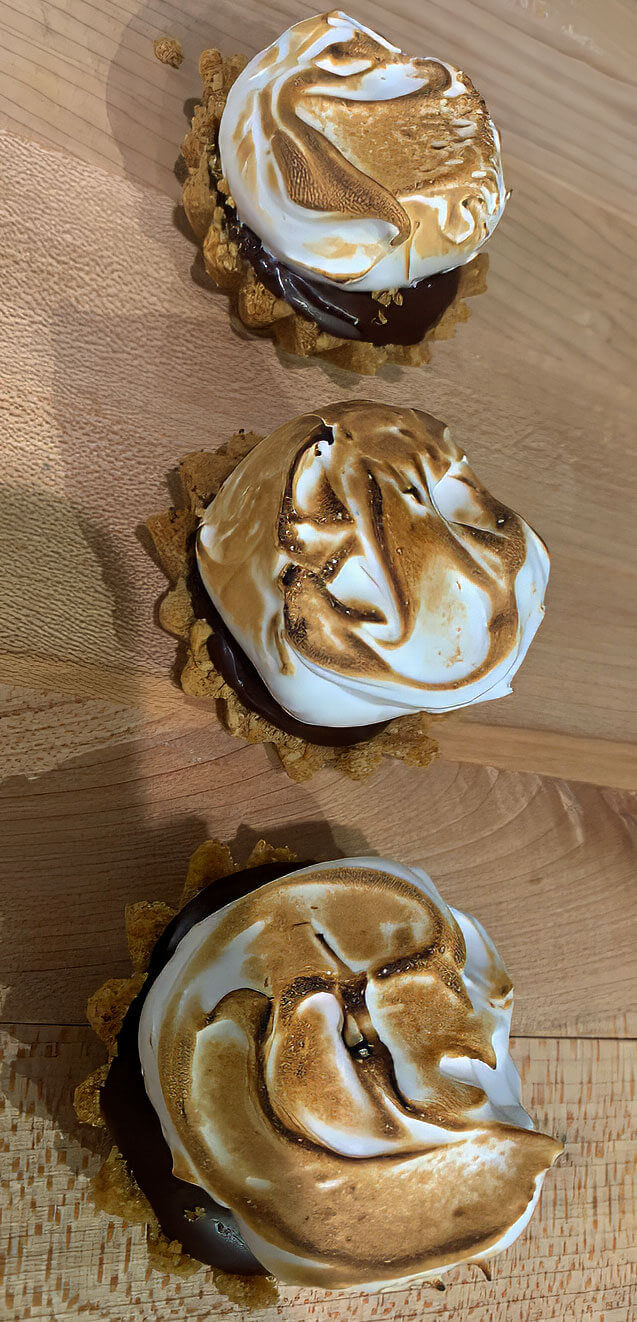 3 smores tarts with chocolate graham and toasted meringue on a wooden board
