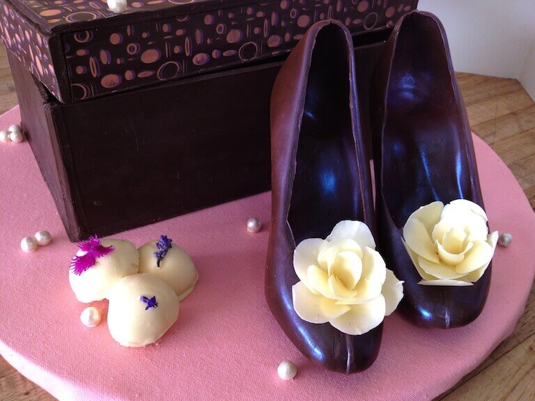 A choclate sculpture featuring a box and a pair high heel shoes with a flower