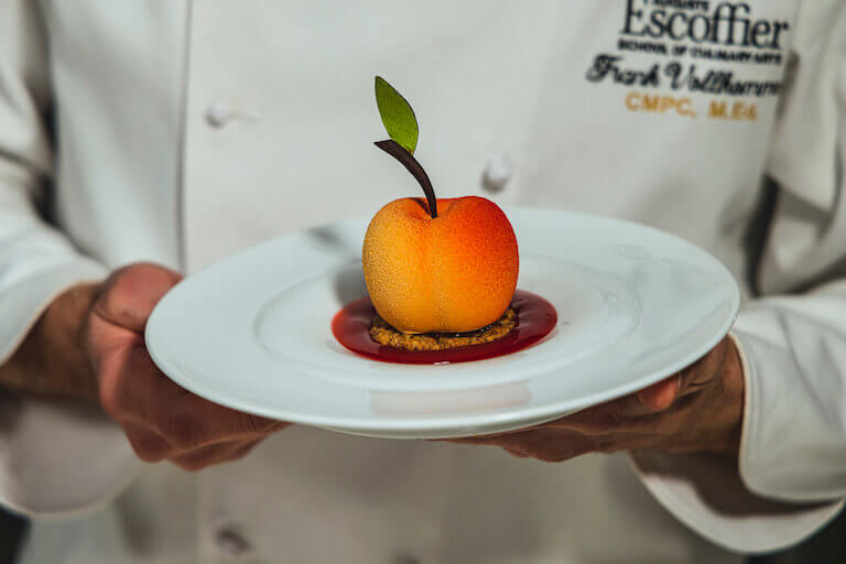 Chef holding a Peach Melba on a white plate
