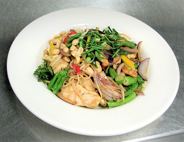Chicken stir-fry with yakisoba noodles, onions, broccoli rabe, peanuts, red onion,yellow and red peppers.