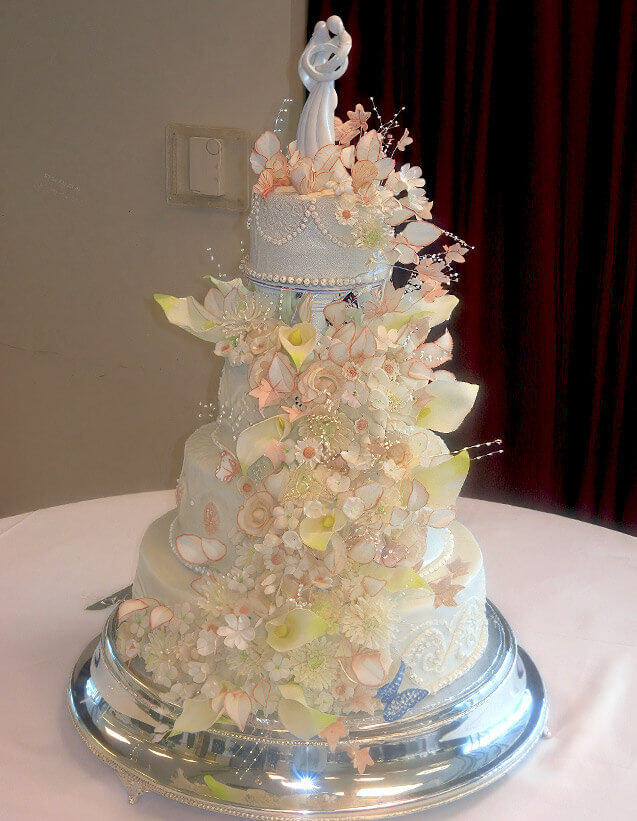 a white layered wedding cake with pink and yellow flowers