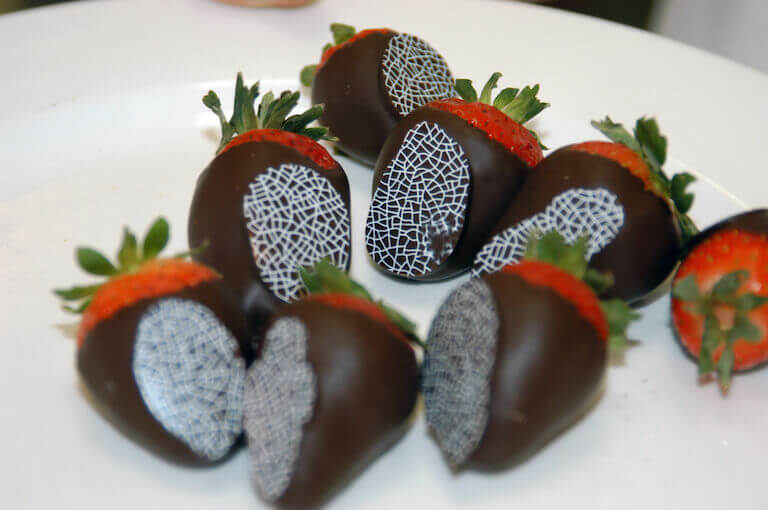 chocolate covered strawberries sit on a white plate