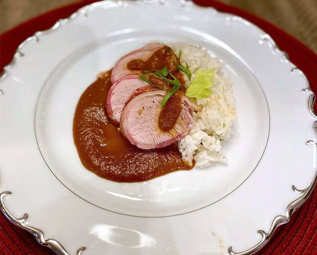 Bacon wrapped pork tenderloin in a apple mole sauce over a bed of whit rice
