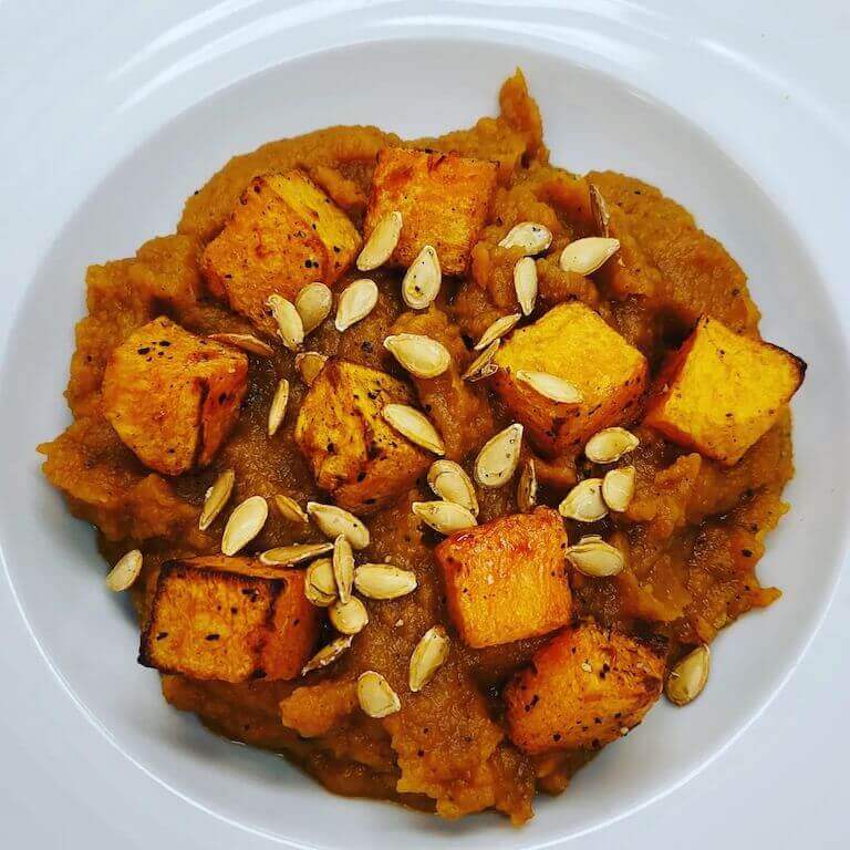 Butternut squash puree topped with seeds in a white bowl