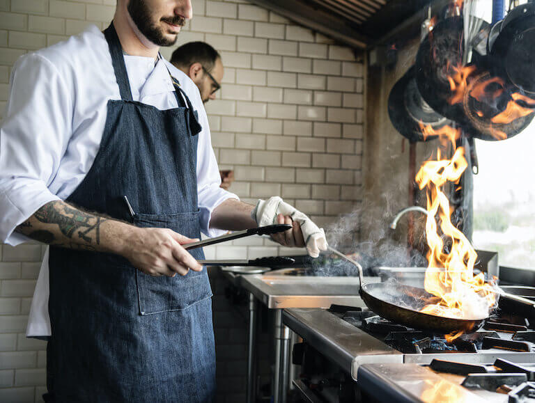 Chef cooking with frying pan on fire