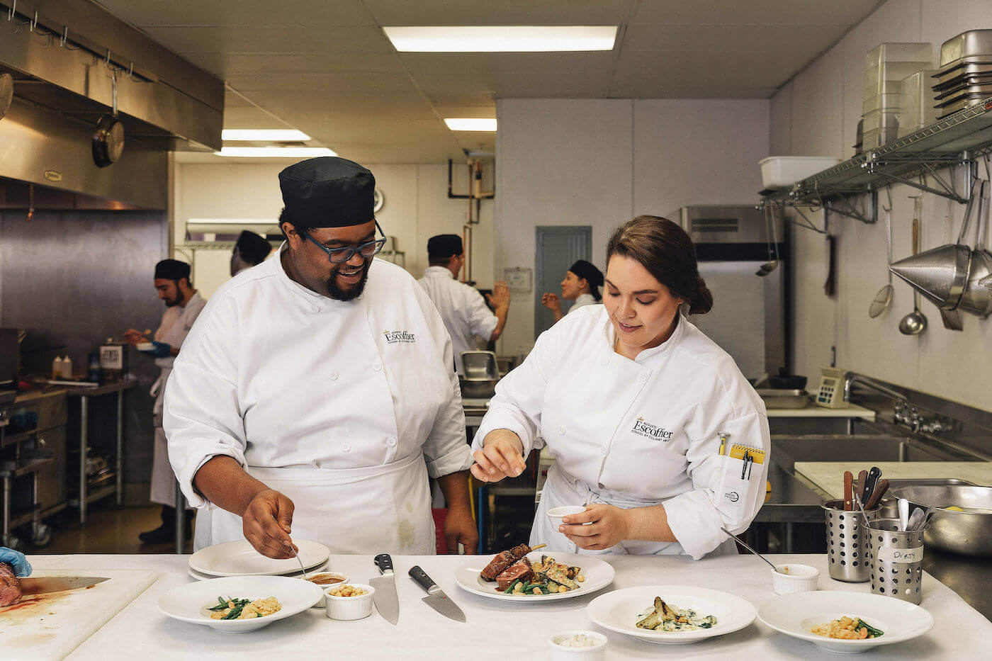 Escoffier culinary students seasoning a plated dish