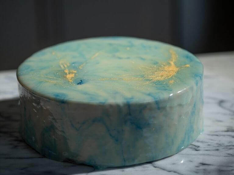 Blue mirror-glazed cake with a smooth, reflective surface that creates a sleek, glass-like appearance, highlighting the vibrant color. 
