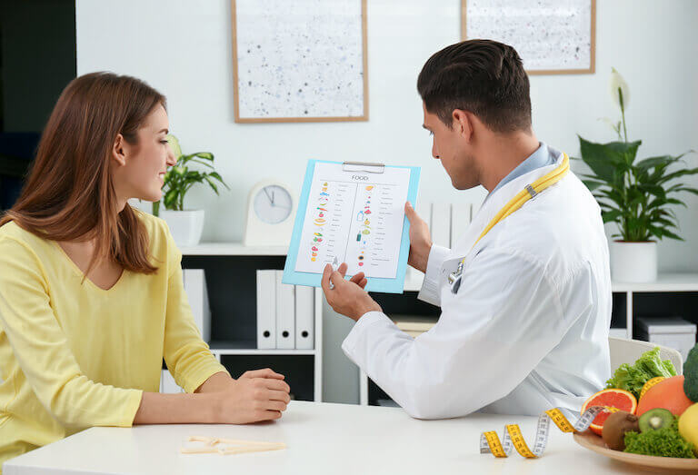 Nutritionist consulting patient at table in clinic