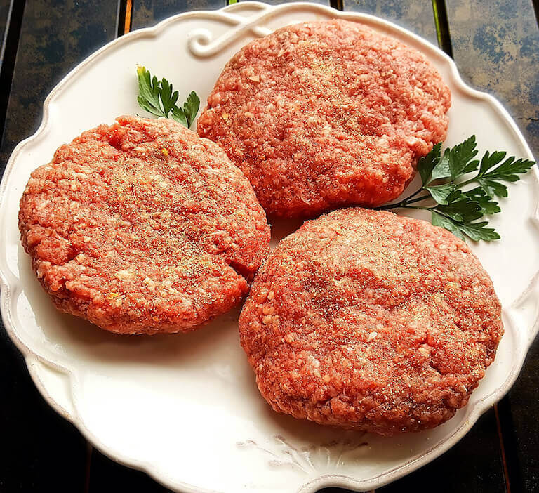 Raw bison burgers on a white plate