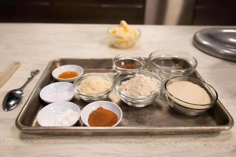 Various ingredients and spices in separate bowls on a metal tray