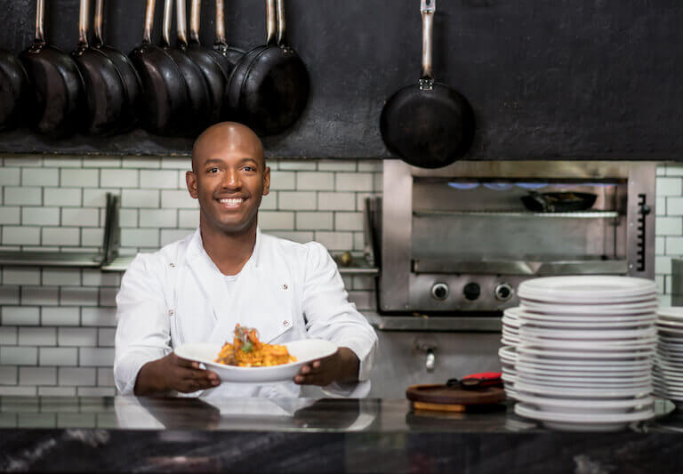 Chef working in a kitchen and showing his plate