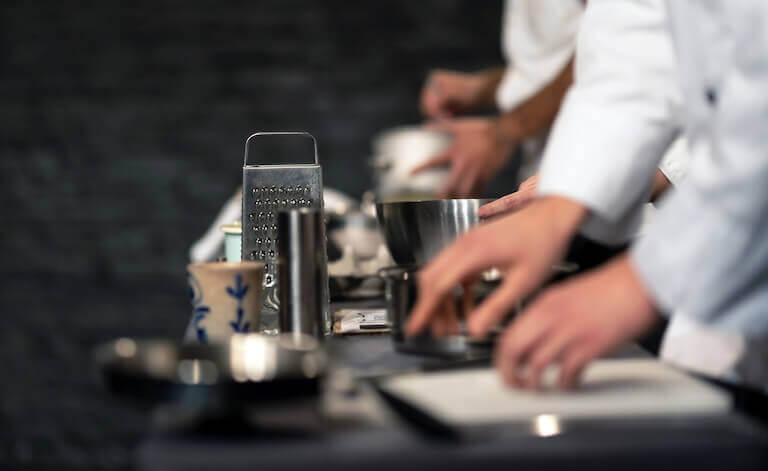 Chefs working in a professional kitchen with a grater