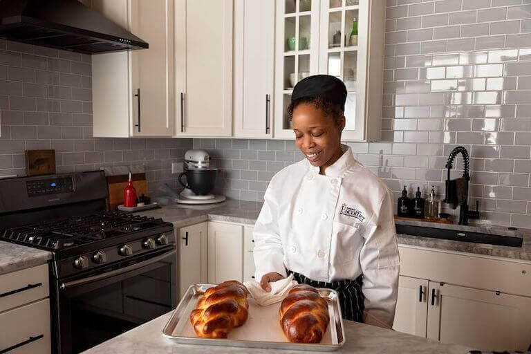 Escoffier online student holding a baking sheet with finished bread
