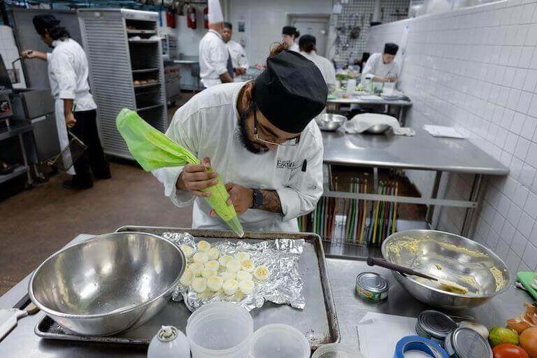 Escoffier student in the kitchen making deviled eggs