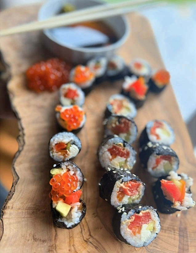 Platter of assorted sushi rolls with seaweed wrap, rice, salmon, cucumber, and salmon roe, served with soy sauce