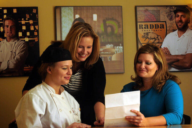 Two women financial aid advisors going over paper with female escoffier student in uniform