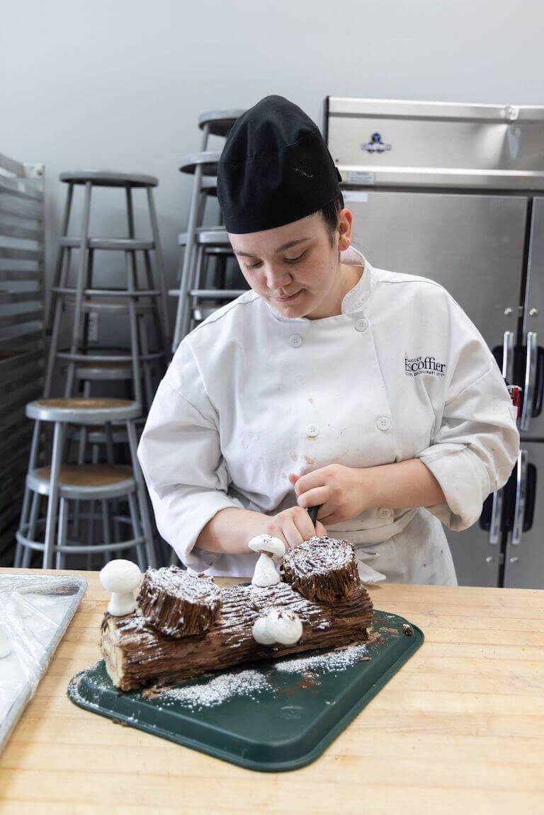 Escoffier student decorating a cake to look like a piece of wood