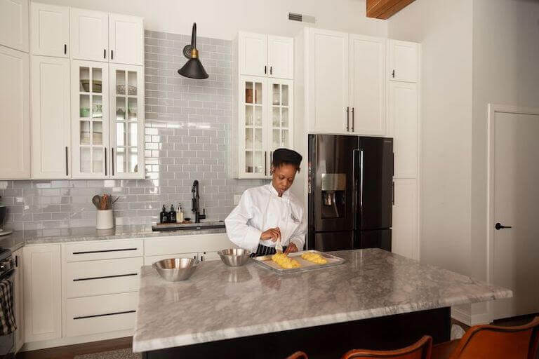 Online student egg washing challah dough in kitchen