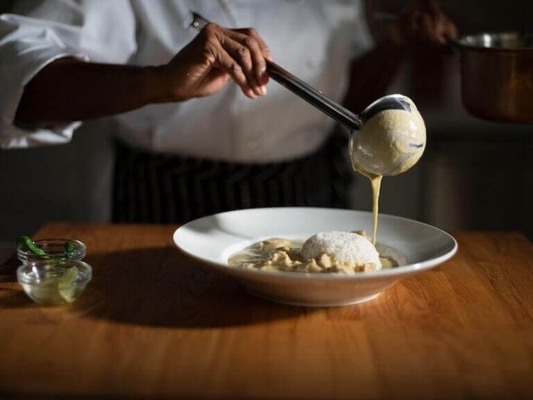 Thai green curry being plated in a white bowl