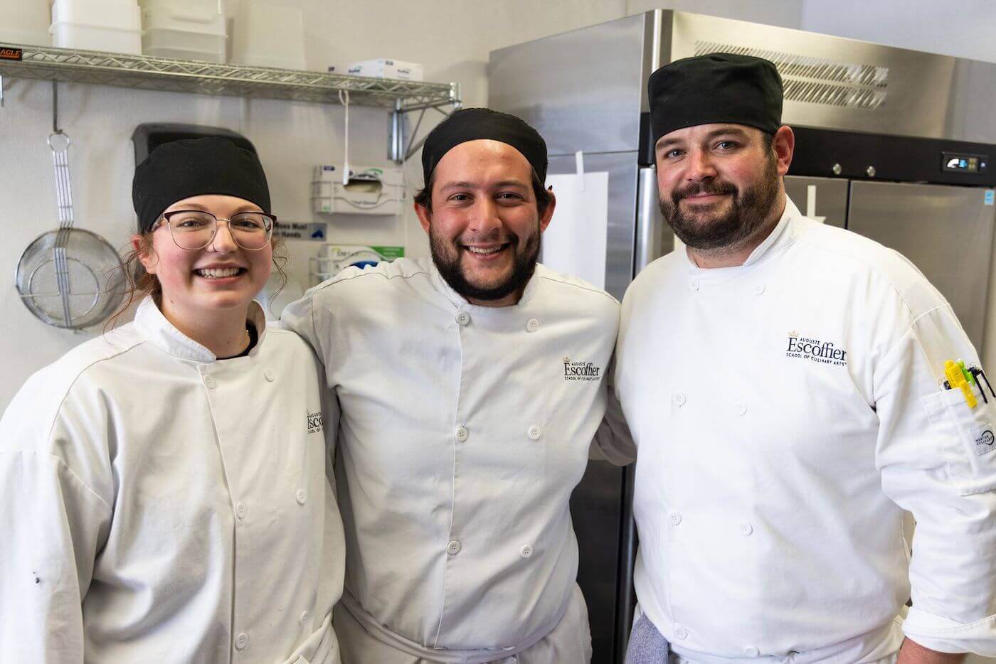 https://www.escoffier.edu/wp-content/uploads/2022/04/Three-Escoffier-students-standing-together-and-smiling-in-a-kitchen-1400.jpeg