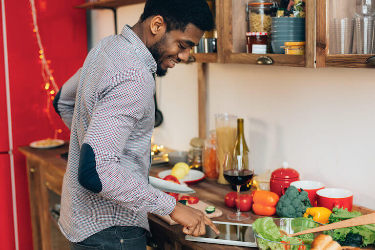 A man is looking at a recipe on his tablet while in the kitchen