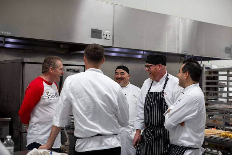 Chef Instructor visiting with students in a kitchen